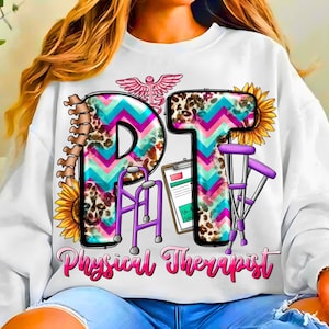 Pode incluir: Camisola branca com um design colorido "PT Physical Therapist". O design inclui um caduceu, coluna vertebral, girassóis e equipamentos médicos. As letras "PT" são decoradas com um padrão de chevron e estampa de leopardo.