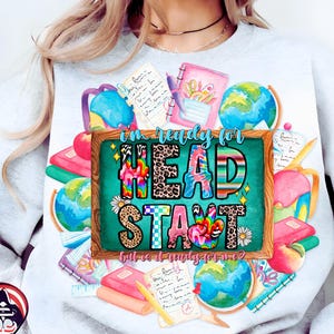 May include: A light gray sweatshirt featuring a colorful graphic design with the words "I'm ready for HEAD START". The design includes school supplies like globes, notebooks, and backpacks, with a peace sign and a daisy.