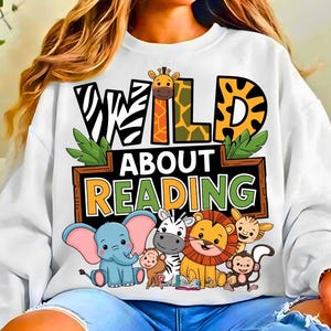 May include: White sweatshirt with a colorful graphic that reads "WILD ABOUT READING." The design features a zebra, giraffe, elephant, lion, monkey, and other animals. The sweatshirt is a crew neck style.