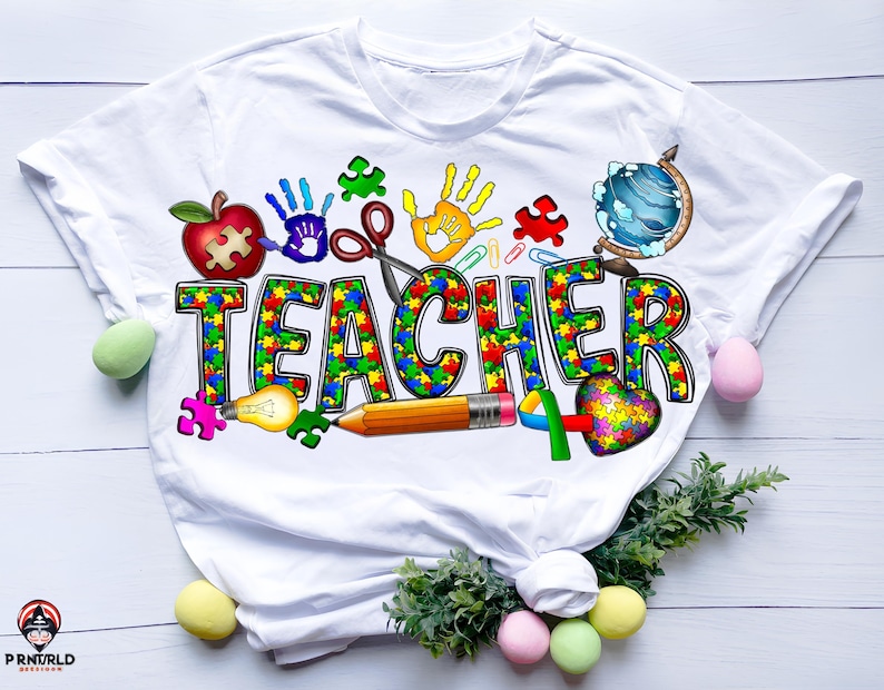May include: White t-shirt with a colorful graphic design that says "TEACHER" in puzzle pieces. The design also includes a lightbulb, pencil, scissors, a globe, a heart, and handprints.