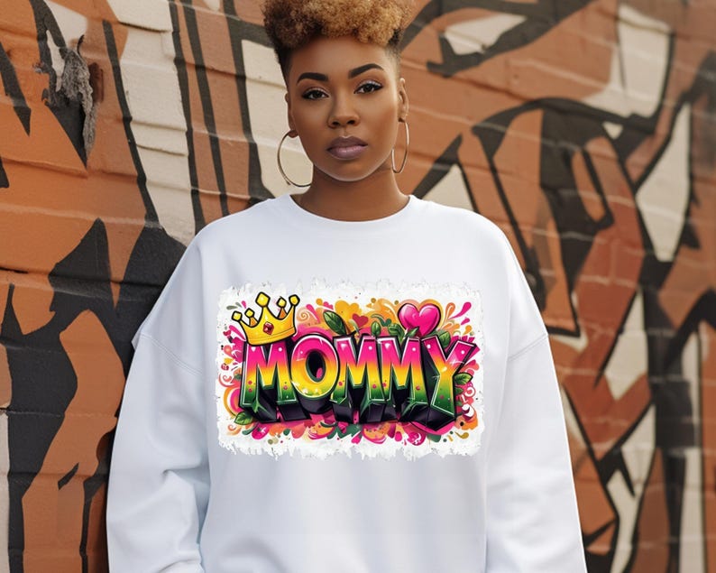 May include: White sweatshirt with a colorful graphic print of the word "MOMMY" with a crown and hearts.
