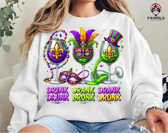 May include: White sweatshirt with a Mardi Gras theme. It features three wine glasses with purple, green, and gold Mardi Gras beads and masks. The text "Drink Drank Drunk" is printed on the sweatshirt.
