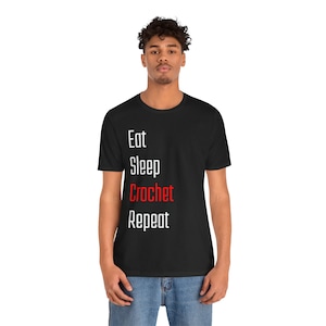 May include: A black t-shirt with white text that reads "Eat Sleep Crochet Repeat". The word "Crochet" is in red.