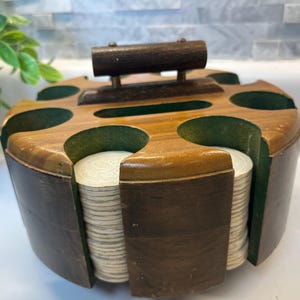 May include: A circular wooden poker chip carousel with a dark brown finish and a central handle. The holder features eight slots lined with green felt, containing stacks of white plastic poker chips with embossed circular patterns on their faces.