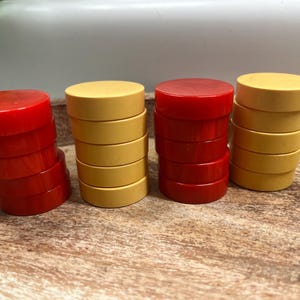 May include: Four stacks of game pieces in red and yellow. The pieces are round and flat, with a smooth, glossy finish. The stacks are arranged on a wooden surface, suggesting a board game or similar activity.