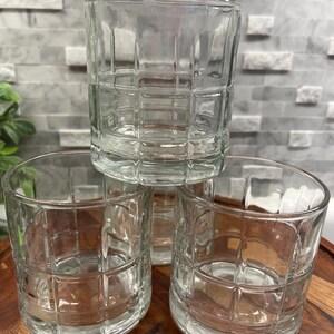Puede incluir: Tres vasos transparentes de vidrio con un dise&ntilde;o de patr&oacute;n cuadrado. Los vasos est&aacute;n apilados uno encima del otro.
