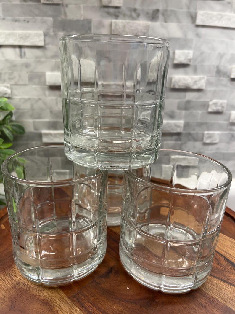 Puede incluir: Tres vasos transparentes de vidrio con un dise&ntilde;o de patr&oacute;n cuadrado. Los vasos est&aacute;n apilados uno encima del otro.