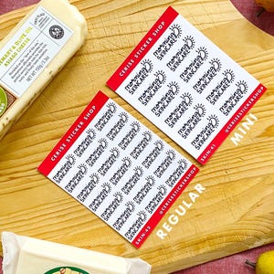 May include: Two sheets of stickers with the text "Morning Skincare" printed on them. The stickers are on a wooden cutting board with a block of cheese, grapes, an orange, an apple, and a pear.