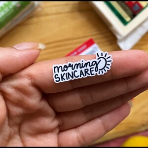 May include: A white sticker with black text that reads "morning skincare" and a sun graphic.
