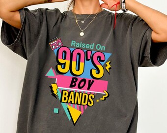 May include: A dark gray oversized t-shirt with a graphic print of a retro boombox, the text "Raised On 90's Boy Bands" in a colorful geometric design.