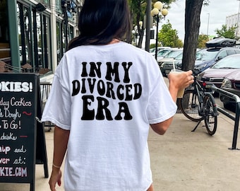 Könnte beinhalten: Weißes T-Shirt mit schwarzem Text, der in einer Retro-Schrift "In My Divorced Era" lautet.