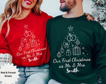 Può includere: Felpe rosse e verde foresta con un design ad albero di Natale. La grafica bianca include fedi nuziali, ornamenti e regali. Il testo sulle magliette recita "Our First Christmas as Mr. & Mrs. Smith."