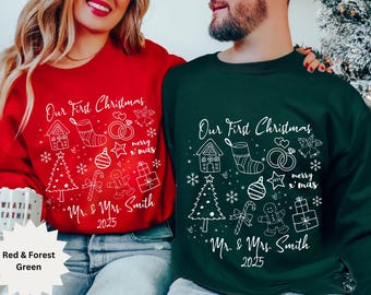 Può includere: Felpe natalizie rosse e verde foresta con la scritta "Our First Christmas" e illustrazioni festive. Il design include una casa, una calza, anelli, una stella, un albero di Natale e un omino di pan di zenzero. Sono stampati anche i nomi "Mr. & Mrs. Smith" e l'anno "2025".
