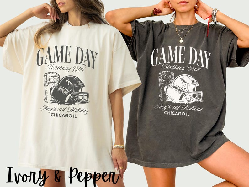 Op de afbeelding: Twee oversized T-shirts, &eacute;&eacute;n ivoorkleurig en &eacute;&eacute;n donkergrijs, met een voetbalthema. Het ontwerp bevat een voetbal, helm en bierpul, met de tekst "GAME DAY" en "Amy's 21st Birthday, Chicago IL."