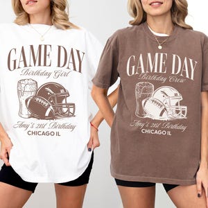 Op de afbeelding: Witte en bruine T-shirts met een voetbalthema. De shirts tonen de tekst "GAME DAY" en "Amy's 21st Birthday, CHICAGO IL." De afbeelding bevat een voetbal, een helm en een biertje.