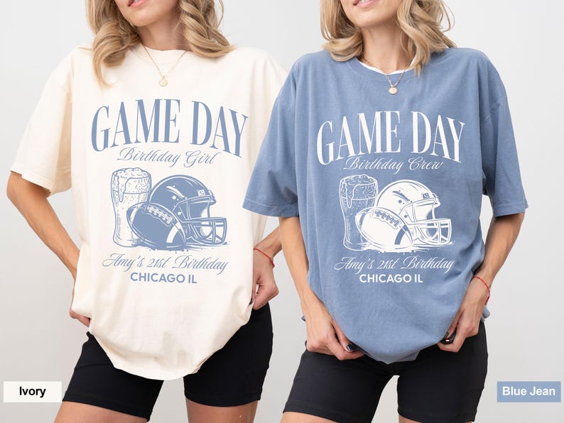 Op de afbeelding: Twee oversized T-shirts, &eacute;&eacute;n ivoor en &eacute;&eacute;n jeansblauw, met een voetbalthema. Het ontwerp bevat een voetbal, helm en bierpul, met de tekst "GAME DAY" en "Amy's 21st Birthday, Chicago IL."