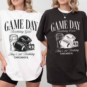Op de afbeelding: Twee oversized T-shirts, &eacute;&eacute;n wit en &eacute;&eacute;n zwart, met een American football thema. Het witte shirt zegt "Game Day Birthday Girl", het zwarte shirt zegt "Game Day Birthday Crew". Beide hebben een football, helm en bier afbeelding, met "Amy's 21st Birthday".