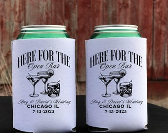 May include: Two white can coolers with the text "HERE FOR THE Open Bar" and illustrations of cocktails. The bottom of the coolers read "Amy & David's Wedding CHICAGO IL 7-15-2025".