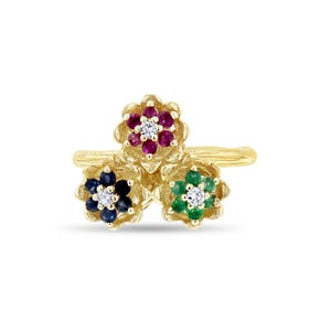 May include: A gold ring featuring three flower clusters. Each flower has a central diamond surrounded by colored gemstones: rubies, sapphires, and emeralds. The ring has a textured band.