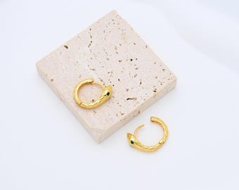 Puede incluir: Un par de pendientes de aro de oro con un diseño de serpiente texturizado y detalles de piedras preciosas verdes.