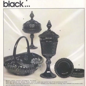 K&ouml;nnte beinhalten: Ein Set aus vier schwarzen Glasst&uuml;cken: eine Bonbonbox mit Deckel, ein Kelch mit Deckel, ein Korb mit Henkel und eine kleine Schale. Alle St&uuml;cke sind mit einem Diamantenmuster verziert. Der Text "The Cameo" ist im Bild zu sehen.