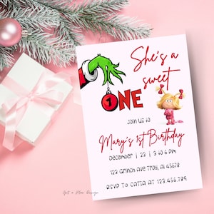 May include: A Christmas-themed birthday invitation with a Grinch-inspired design. The invitation features a green Grinch hand holding a red ornament with the number "1" on it. The text "She's a sweet one" is written in red. The invitation also features a cartoon image of Cindy Lou Who from the movie "How the Grinch Stole Christmas". The text "Join us for Mary's 1st Birthday" is written in red. The invitation includes the date, time, and location of the party. The text "RSVP to Catia at 123.456.789" is written in black.
