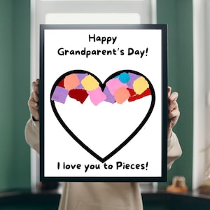 May include: A framed print with a black border, featuring a black heart outline filled with colorful paper pieces. The text "Happy Grandparent's Day!" is above the heart, and "I love you to Pieces!" is below.