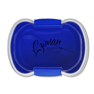 May include: A blue container with a clear rim and a blue lid. The container has a spoon inside. The text "Lyman clothing co." is printed on the container.