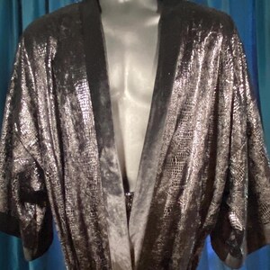 May include: A black velvet robe with a silver snakeskin pattern. The robe has a shawl collar and long sleeves.