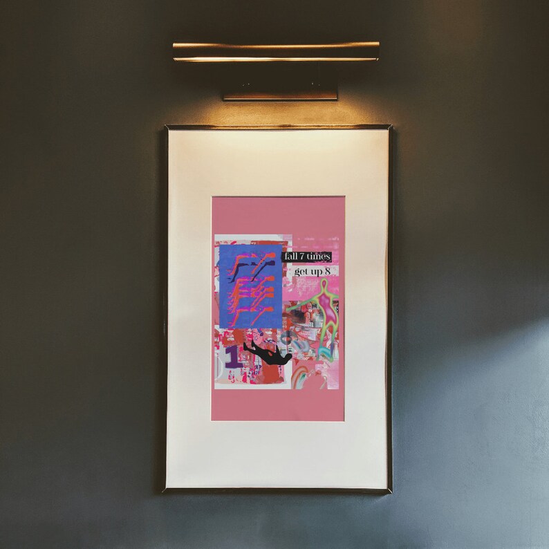 May include: A framed print with a pink background and a collage of colorful images. The text "fall 7 times get up 8" is printed in black on a white rectangle.