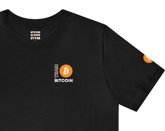 May include: Black t-shirt with a white "Team Bitcoin" logo and a Bitcoin symbol in an orange circle. The shirt also has a small orange Bitcoin symbol on the sleeve.