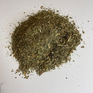 May include: A pile of dried, green, leafy herbs. The herbs are finely chopped and appear to be ready for use in cooking or for making tea.
