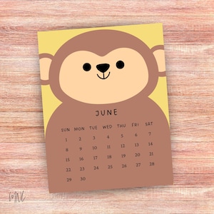 Puede incluir: Un calendario de junio con un dise&ntilde;o de mono de dibujos animados. El mono es marr&oacute;n con una cara y orejas de color canela claro, sobre un fondo amarillo. La cuadr&iacute;cula del calendario es marr&oacute;n con n&uacute;meros negros.