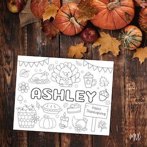 May include: Black and white Thanksgiving-themed coloring page with the name "Ashley" in large letters. The page features a turkey, pumpkin spice latte, pie, and other festive illustrations. A sign reads "Happy Thanksgiving."