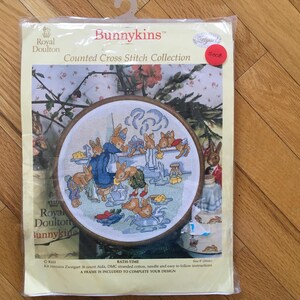 May include: A Royal Doulton Bunnykins counted cross stitch kit. The kit shows a circular embroidery hoop with a colourful scene of bunnies in a bathroom setting. The packaging includes the text "BATH-TIME" and "A FRAME IS INCLUDED TO COMPLETE YOUR DESIGN."