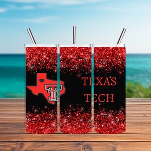 May include: Three red glitter tumblers with black lids and straws. The tumbler on the left has a red outline of the state of Texas with a red heart and the letter "T" inside. The tumbler in the middle has the word "TEXAS" in red letters. The tumbler on the right has the words "TEXAS TECH" in red letters.