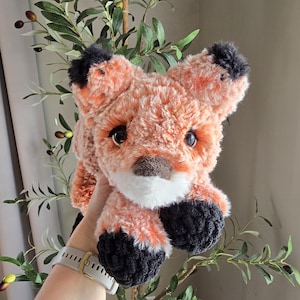 Puede incluir: Un juguete de peluche de zorro con pelaje naranja, orejas y patas negras y detalles blancos alrededor de la nariz y la boca.