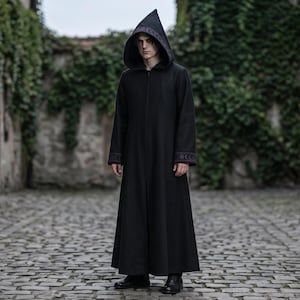 Pode incluir: Uma túnica preta com capuz que chega ao chão, com mangas compridas e acabamentos decorativos roxos nos punhos e na borda do capuz. A peça apresenta um capuz pontiagudo estruturado e um corte reto simples que chega aos tornozelos.