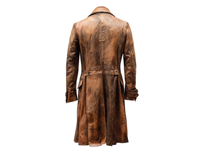 K&ouml;nnte beinhalten: Ein langer, brauner Ledermantel mit Used-Look. Der Mantel hat einen Reverskragen, Kn&ouml;pfe und Taschen. Die R&uuml;ckansicht zeigt einen G&uuml;rtel in der Taille und einen langen, flie&szlig;enden Rock.