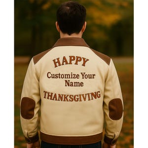 May include: Cream-colored jacket with brown accents on the shoulders, elbows, and collar. The back of the jacket features the words "HAPPY", "Customize Your Name", and "THANKSGIVING" in brown lettering. A stylish outerwear piece.