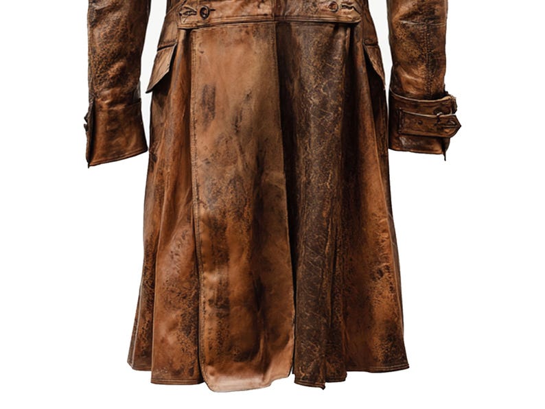 K&ouml;nnte beinhalten: Ein brauner Ledermantel mit einem abgenutzten, strukturierten Aussehen. Der Mantel hat eine lange L&auml;nge, Kn&ouml;pfe und Taschen. Die &Auml;rmel haben gekn&ouml;pfte Manschetten. Der Stil deutet auf eine Vintage- oder Steampunk-&Auml;sthetik hin.