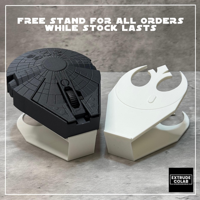May include: A black computer mouse shaped like a circular spacecraft with intricate surface detailing, resting on a white plastic stand. Beside it is an identical white stand featuring a cutout of a stylized rebel alliance symbol emblem.