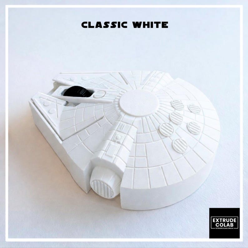 May include: A white computer mouse shaped like a spaceship with a circular body and a forward-facing cockpit. The top surface features a grid pattern and a black scroll wheel. The text CLASSIC WHITE is printed above, and EXTRUDE COLAB is below.