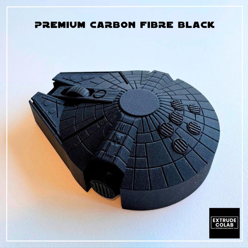 May include: A matte black computer mouse shaped like a spaceship with intricate circular and grid-like surface detailing. The text "PREMIUM CARBON FIBRE BLACK" is printed at the top, and a small logo box for "EXTRUDE COLAB" is in the bottom corner.