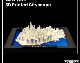 Puede incluir: Una maqueta de ciudad de Nueva York impresa en 3D en blanco, que se muestra en un marco negro con una base azul. El modelo muestra el horizonte de Manhattan con muchos edificios y el agua circundante.