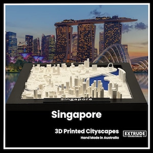Op de afbeelding: Een wit 3D-geprint model van de skyline van Singapore, ingelijst in zwart. Het model toont de iconische gebouwen van de stad, waaronder het Marina Bay Sands hotel en de Gardens by the Bay. De tekst "Singapore" is op het model gedrukt. De tekst "3D Printed Cityscapes" en "Hand Made in Australia" zijn onder het model gedrukt.