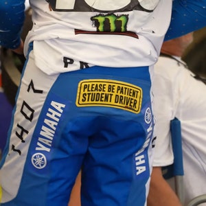 May include: A blue and white Yamaha motocross racing pants with the number 407 on the side and a yellow sticker that says "Please be patient student driver".
