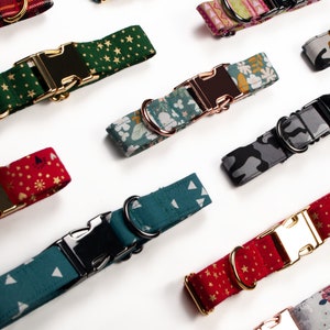 Pu&ograve; includere: Una collezione di collari per cani con vari motivi, tra cui stelle, floreali e mimetici. Ogni collare presenta una fibbia in metallo e un anello a D per l'attacco del guinzaglio. I collari sono in tonalit&agrave; di verde, rosso e blu, con finiture dorate e argentate.