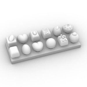Könnte beinhalten: Eine weiße Schachtel gefüllt mit verschiedenen Schokoladen. Die Schokoladen haben verschiedene Formen, darunter Herzen, Kreise und Quadrate. Einige der Schokoladen haben dekorative Designs auf der Oberseite.
