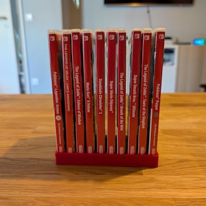 Op de afbeelding: Een rode spelcassettehouder met meerdere Nintendo Switch-gamecases. De rode cases hebben witte tekst met titels als "Pokémon Legends: Arceus", "Mario Kart 8 Deluxe" en "The Legend of Zelda: Tears of the Kingdom".